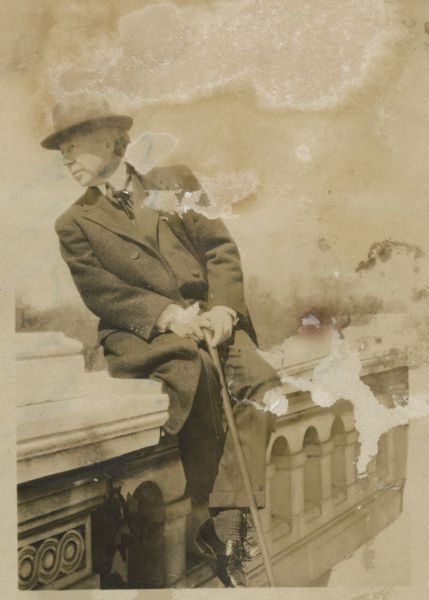 Frank Lloyd Wright sitting on a stone balustrade.