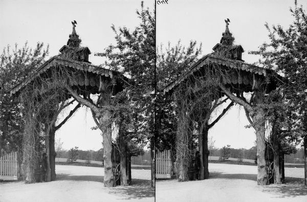 Elaborate gateway in the shape of an arch to the National Soldiers Home. The gateway is made of trees with a miniature building on top.