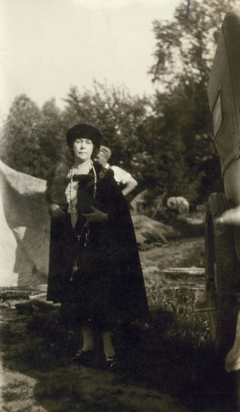 Mrs. Miriam Noel Wright, second wife of Frank Lloyd Wright.  Mrs. Wright is standing behind a car wearing a cape with a fur collar.