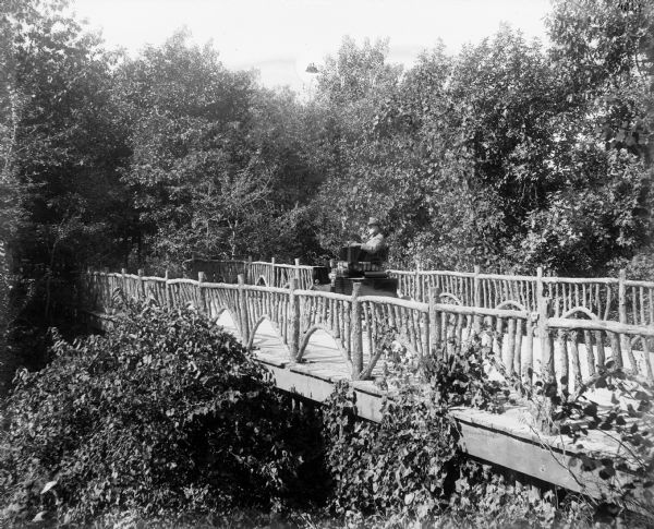 A.G. Zimmerman parked on an artfully rustic, wooden bridge in his automobile, a "locomobile steamer," on Mendota Drive.