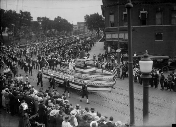 Labor Day parade on the Capitol Square, at the State Street corner, featuring a float shaped like a boat and carrying a naval gun barrel. Gun barrel and float made by the Four Lakes Ordinance Co. "To help make the world safe for democracy."