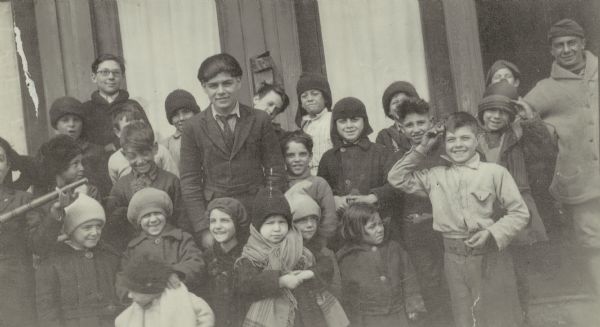 Group portrait of children and one adult, all probably of Italian descent.
