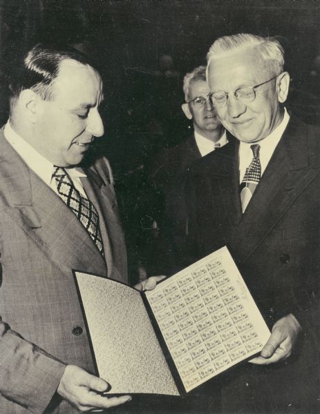 Governor Oscar Rennebohm receiving a full sheet of the 1948 centennial stamp.