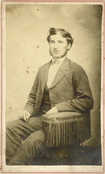 Studio portrait of W.H. Wheeler seated in a tassled chair.