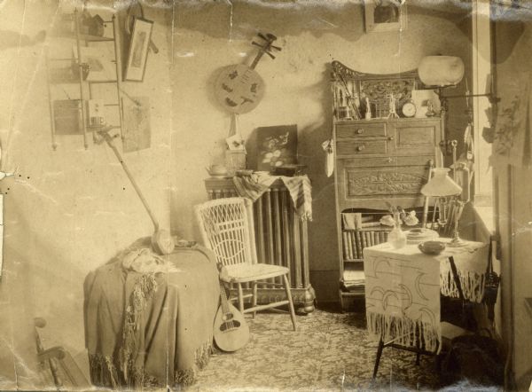 A room at Rockford College with a table and chair, and several stringed instruments.