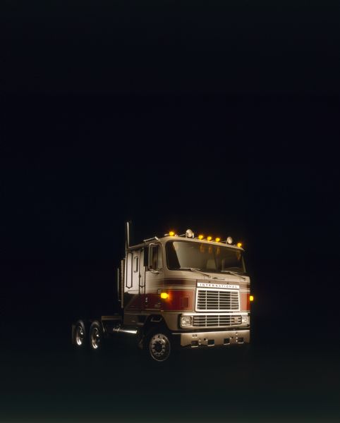 Color photograph of an International Transtar Eagle semi tractor painted white with brown and orange stripes, 3/4 view (front) of right side.