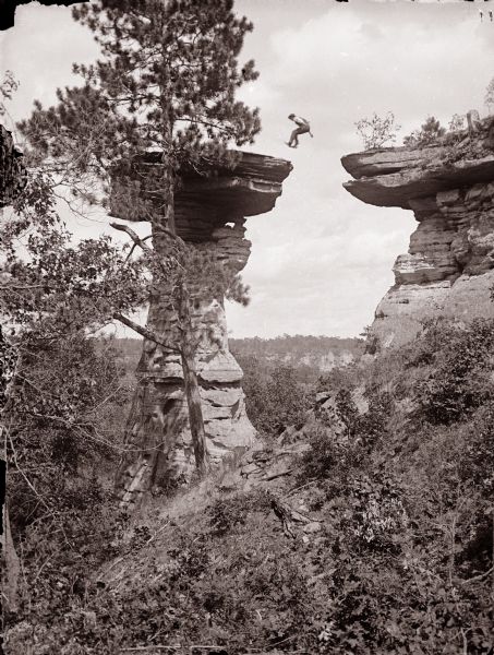 Man leaping the chasm with feet forward, about to land.