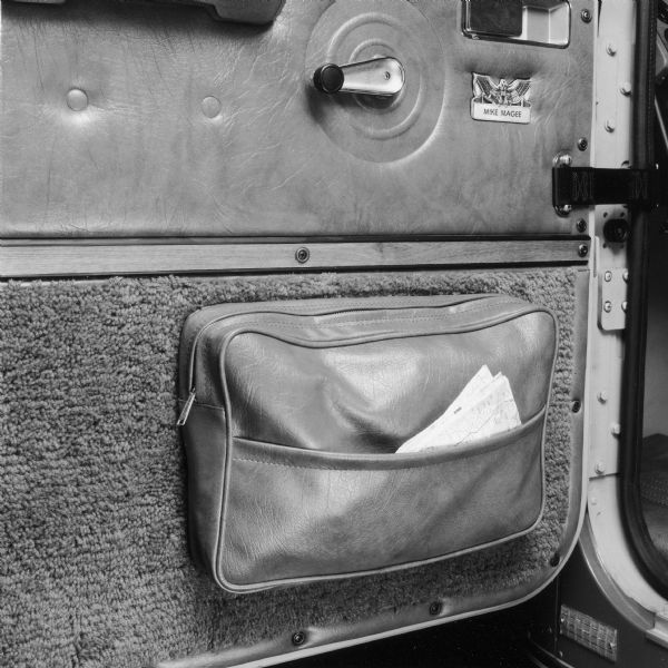 Close-up of the driver's side door of an International Transtar Eagle semi tractor.  Shows the windown crank, map pocket and a nametag that reads: "Mike Magee."