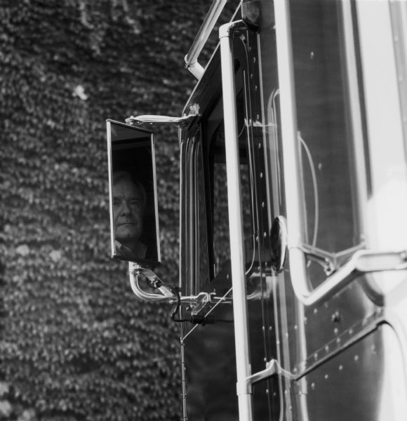 Close-up of the driver's side mirror of an International Transtar Eagle semi tractor. A man's face is reflected in the mirror.