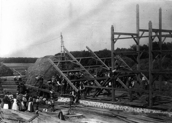 Elevated view of a barn raising on the farm of Alva Paddock in the township of Salem on Geneva Road, Highway 50.