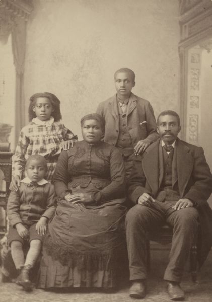 Studio portrait in front of a painted backdrop of Martha and Notley Henderson with their three children. Their son Allen is standing. The Hendersons were early African American settlers in Madison.