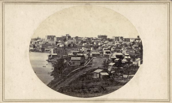 John S. Fuller took this image of the third Wisconsin State Capitol (the second in Madison), from Governor Farwell's Octagon House, probably early in 1862. Also visible in the downtown are the Dane County Courthouse and St. Raphael Catholic Church. Frederick A. Sprecher's brewery (later Fauerbach's) is in the middle ground on the left. The foreground provides a glimpse into many backyards.