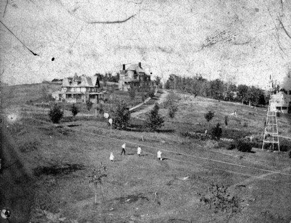 View of University Heights, including the Maurer House, the Buell House, and the Stevens House. In the foreground are Gertrude, Margaret, Harry, and Helen Knowlton. The photograph was taken from a tower in the Knowlton House.