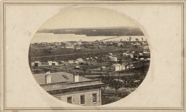 Fuller made this photograph of the University District and railyards from the roof of Main Hall (now Bascom Hall), about 1860-1862.  Completion of that building in 1860 afforded an elevation for unprecedented views of the city.  In the foreground is South Hall and in the distance, beyond a sparsely populated neighborhood, is the railroad causeway over Brittingham Bay.