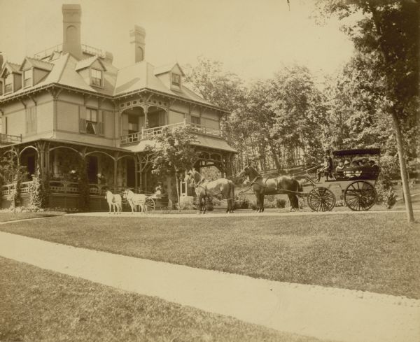The estate known as "Snug Harbor" built by George Sturges in 1884 and owned by the Sturges family until about 1908. In the driveway in front is a child in a carriage pulled by two ponies, and on the right is a group of people sitting in a horse-drawn carriage.