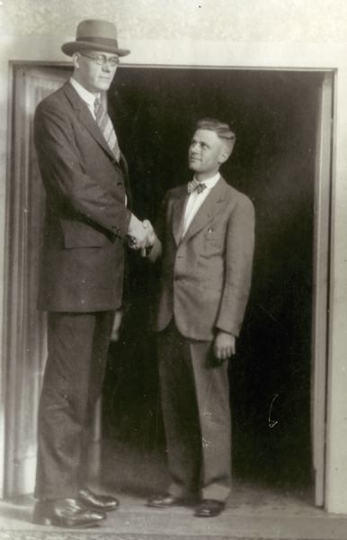 Clifford Thompson, who at 8 feet, 8 inches in height was the tallest man in America, shakes hands with a newspaper man of average height.