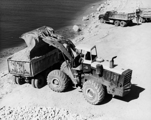 International H-100C Payloader loading lime rock into a dumptruck.  The H-100C was built by the Hough subsidiary of International Harvester.  According to the original caption, this machine belonged to Charley Toppino & Sons, general contractors, material suppliers, and excavators of Key West, Florida.