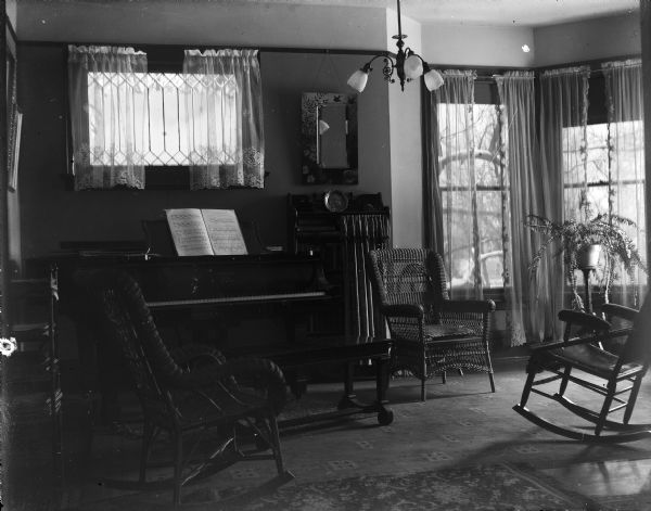 Interior view of the living room in the house of Albert Zimmerman at 746 East Gorham Street with wicker chairs and a piano.