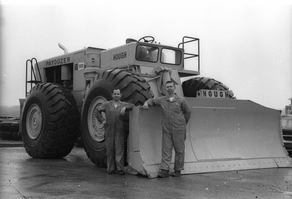 Bob Johnson and Karl Kordas standing in front of the Hough D500 paydozer they helped to assemble. They are likely standing on the grounds of the Frank G. Hough Company's factory at Libertyville, Illinois. The Hough company was a subsidiary of International Harvester.