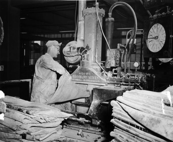 Victor Marten, a worker at the Gillette factory owned by the United States Rubber Company, feeding rubber into a Banbury mixer.  During World War II the government purchased the plant after which it produced ordnance for the war effort.  This photograph was taken after the plant reconverted to tire production in 1944.
