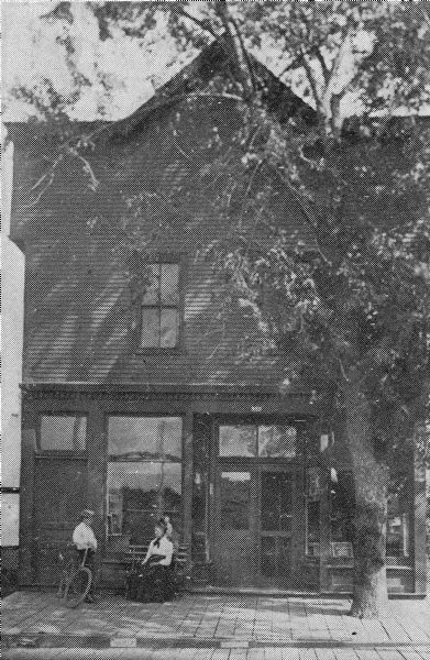 Exterior view of the Wingra Park Advancement Association Hall, with a man and a woman posing in front of the building.