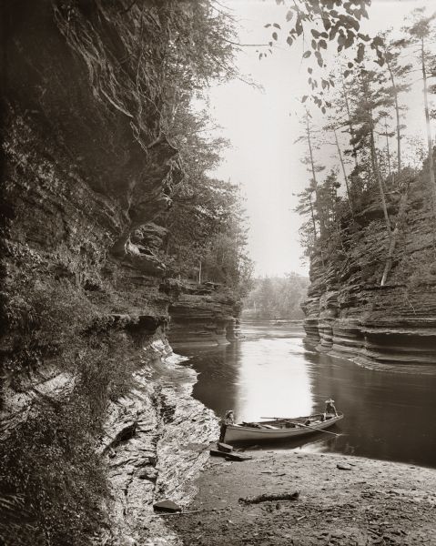 Downstream from channel behind Steamboat Rock. Two children are standing near a rowboat in the water at the shoreline.