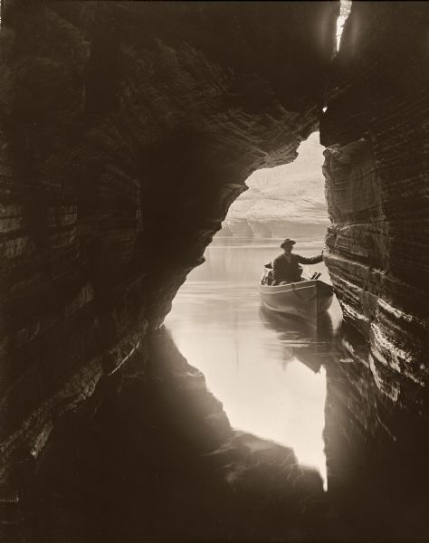 View out of Skylight Cave towards a man in a boat at the entrance to the cave.