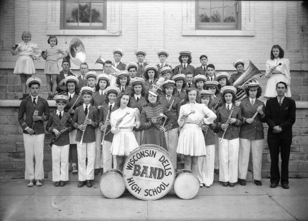 Group portrait of the Wisconsin Dells High School Band in uniform, posing with their instructor.