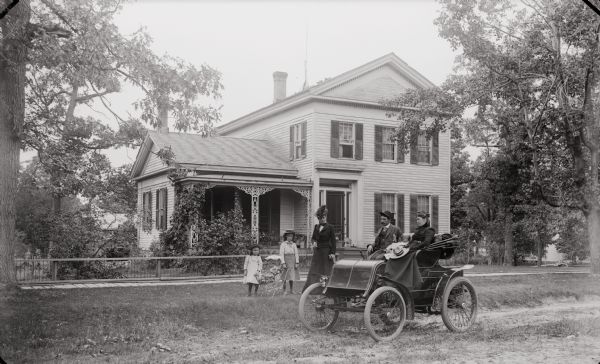 The family of  H.H. (Henry Hamilton) Bennett, posing formally in and around a car parked in front of their house.