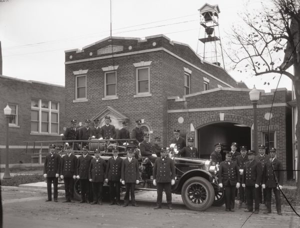 Members of the Kilbourn Fire Department posing in uniform with a fire truck in front of the fire station on Oak Street.