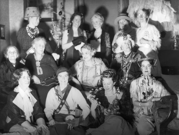 A group of women dressed festively and comically for a party. From left to right in the back row are Evaline Bennett, Blanche Foster, Edith Whitney, Rena Palmer and Mrs. Barney. From left to right in the middle row are Mrs. Drumb, Mrs. Shate, Nora Dixon and Miss Conway. Seated on the floor left to right are Miriam Bennett, Marge Johnson, Ruth Bennett Dyer and Nellie Dixon.