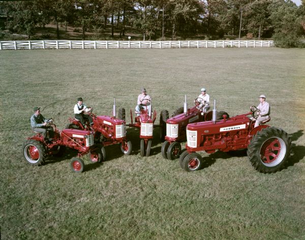 Color advertising photograph of McCormick Farmall tractors with red and white paint schemes lined up in a semi-circle in a field. Tractors include (L to R): the Cub, 130, 230, 350, and 450.
