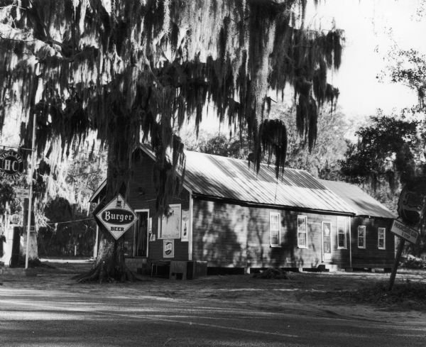 Exterior view of the Progressive Club with an advertisement for Burger Beer sign in front. In Johns Island and run by Esau Jenkins.