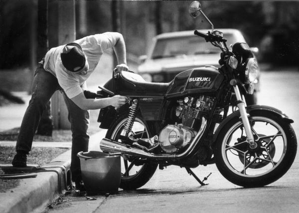Corky Barker washing down his motorcycle in front of his home at 2734 South Superior Street.