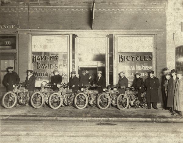 Men on Harley Davidson motorcycles lined up in front of Harry McDaniels' Bicycle and Motorcycle shop at 111 State Street.