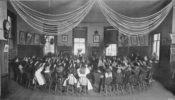 Students raise their hands in a kindergarten class at Crow School.