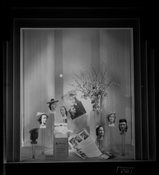 "Madmoiselle" hat window at Manchester's Department Store. A sign in the window reads: "Here They Are! Copies or adaptations of prize-winning hats, Mademoiselle college hat design contest, recently shown at the Waldorf-Astoria Hotel, New York."
