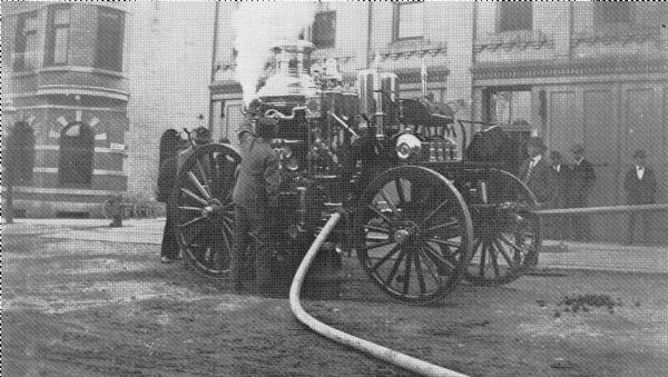 Keyes steam engine undergoing routine testing in front of Madison's old Central Fire Station, 10 South Webster Street. The water is being drawn from a cistern which the City installed in front of the engine house.