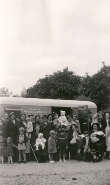 Mothers and infant children stand in front of the Brown County Trailer.