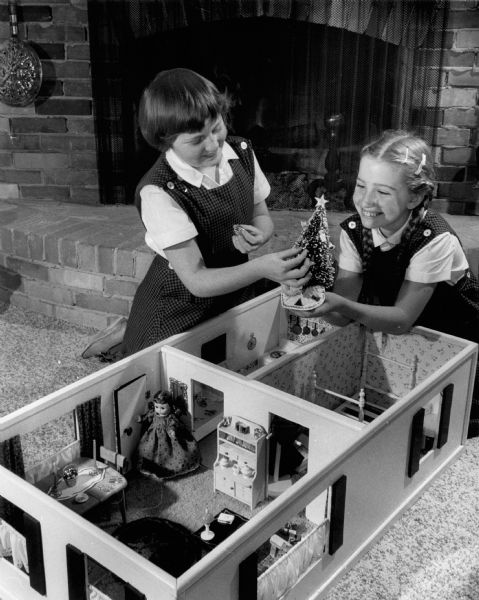 Carrying out the "Babes in Toyland" theme at the home of Mr. and Mrs. Lloyd W. Shamburek, 140 W. Good Hope Road. Peggy (left), arrranges the furniture with Carol Rueping, 10, of North Lake Drive, also from Fox Point.