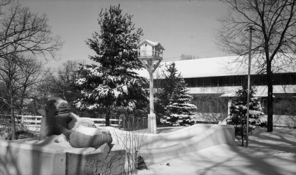 Exterior view of Dell View Hotel driveway on a winter day. A snow-covered stone gargoyle statue is in the foreground. The photo was taken by Ruth Bennett Dyer.
