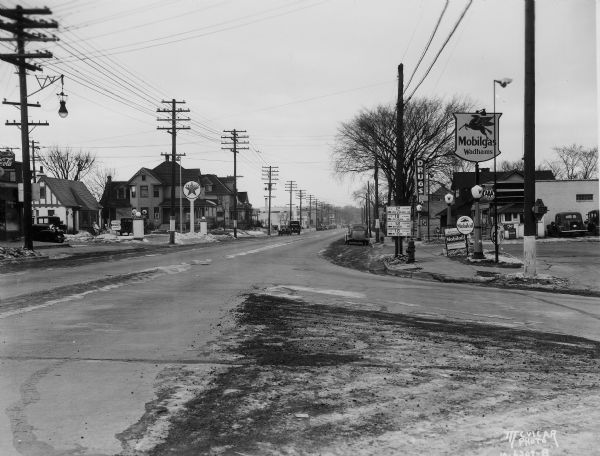 South Park Street (Hwy 12 & 14 & 18), looking North from the intersection at Olin Avenue. The view includes Moore's Wadhams Mobilgas Service Station, 1129 South Park Street, Bartsch's Texaco Station at 1118 South Park Street, and Southside Pharmacy, 1123 South Park Street.