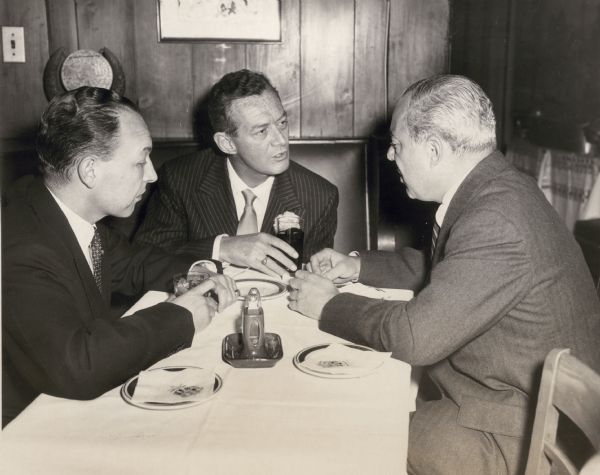 Robert Sarnoff, David Sarnoff and Sylvester "Pat" Weaver wearing suits, seated at a table.