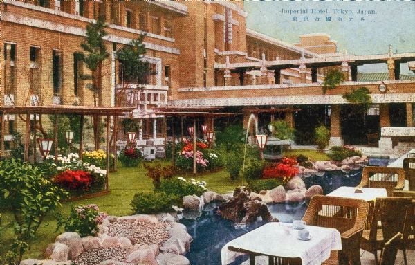 Courtyard and gardens at the Imperial Hotel, Tokyo, Japan, designed by Frank Lloyd Wright.  Wicker tables and chairs, probably used for dining outside, line one side of the courtyard.