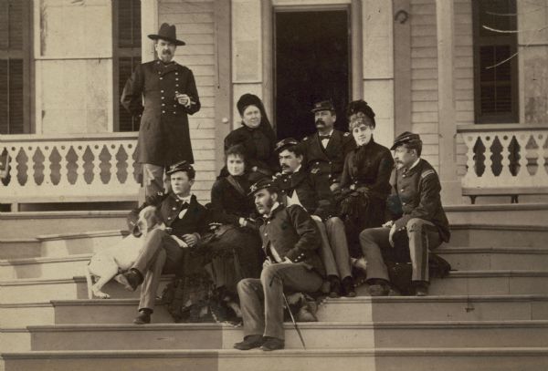 Informal portrait of the Sturgis Family. General Samuel Davis Sturgis, and Jerusha Wilcox Sturgis, are seated with soldiers outside of building.