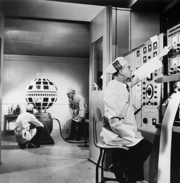 Three men testing the Bell System's Telstar experimental communications satellite at the Bell Telephone Laboratories before being sent to Cape Canaveral, Florida.