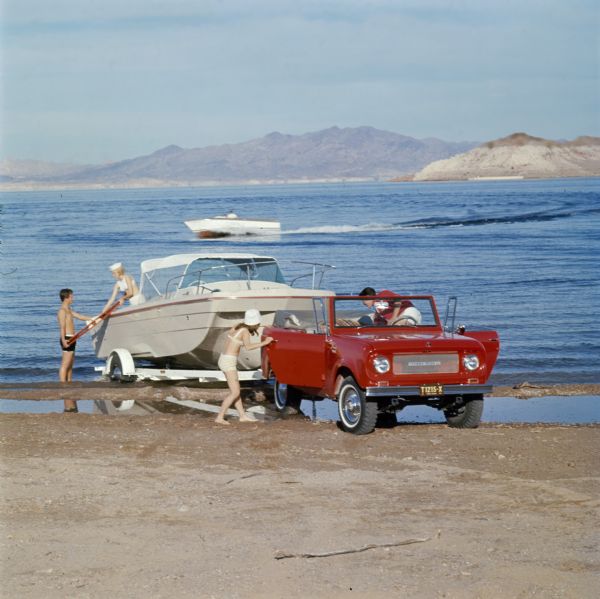 Color advertising photograph of two young couples loading a boat onto a trailer pulled by an International Scout pickup.