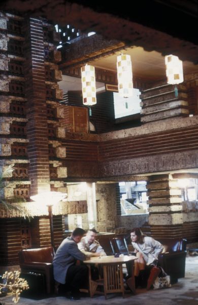 Seating area in the lobby of the Imperial Hotel, Tokyo, Japan.  A group of people are seated in one of the lobby seating areas.  The hotel was designed by architect Frank Lloyd Wright.