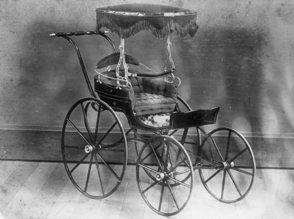 Children's carriage with fringed canopy, produced at children's carriage factory.