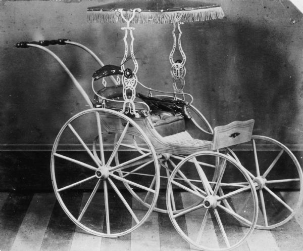 Children's carriage with small fringed leather canopy, produced at children's carriage factory.